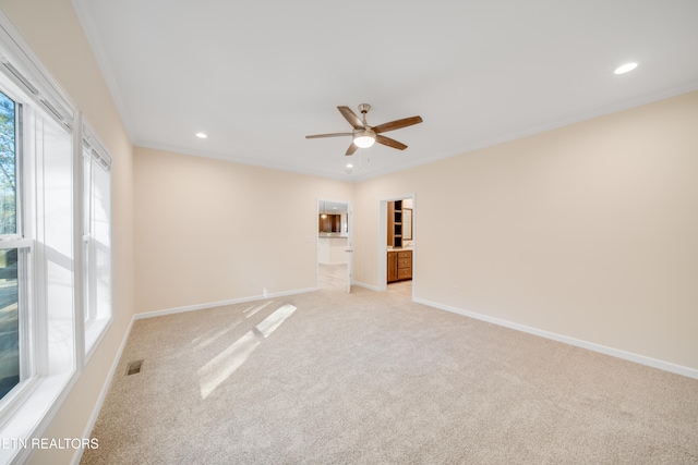 empty room featuring ornamental molding, plenty of natural light, and light carpet