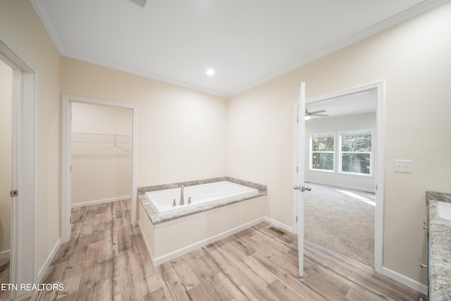 bathroom with crown molding, hardwood / wood-style floors, and a washtub