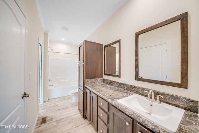 full bathroom with hardwood / wood-style flooring, tub / shower combination, vanity, ornamental molding, and toilet