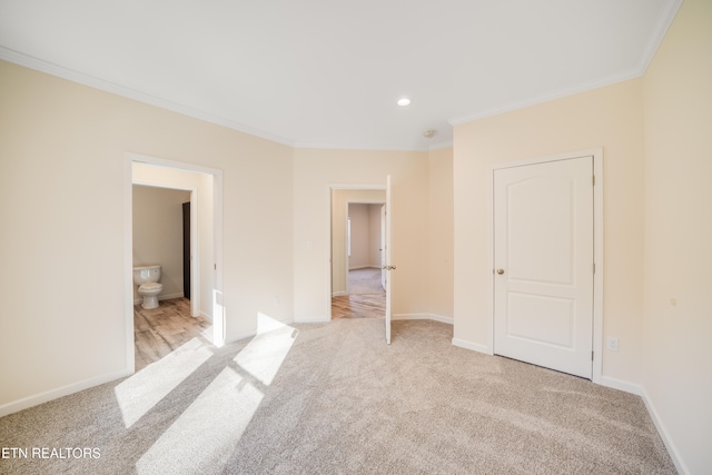 unfurnished bedroom featuring ensuite bathroom, ornamental molding, and light carpet