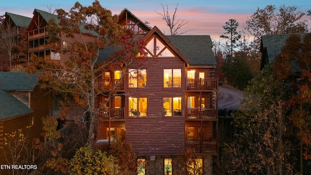 back house at dusk featuring a balcony