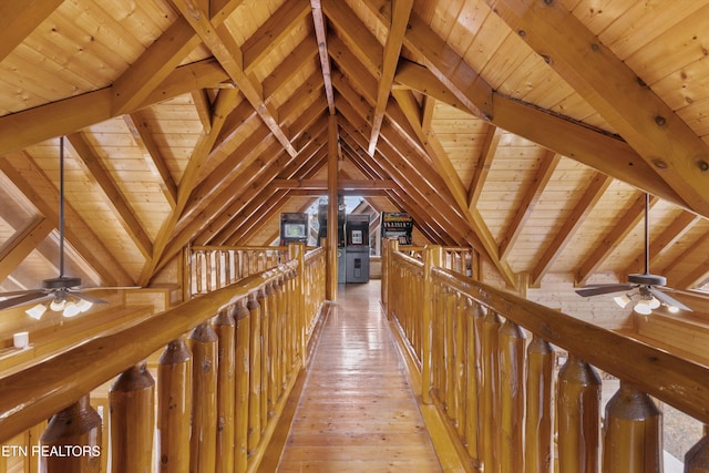 hallway with wooden walls, lofted ceiling with beams, light hardwood / wood-style floors, and wooden ceiling