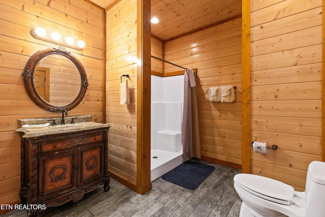 bathroom with vanity, wooden walls, a shower with shower curtain, hardwood / wood-style flooring, and toilet