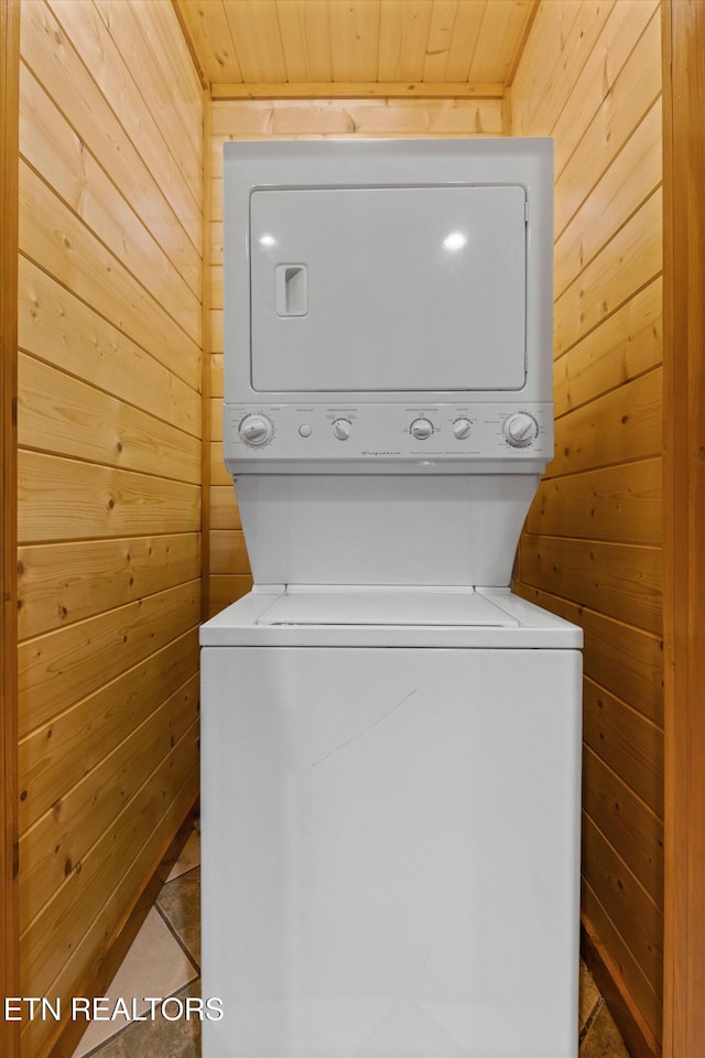 laundry room featuring wooden ceiling, stacked washer and dryer, and wooden walls