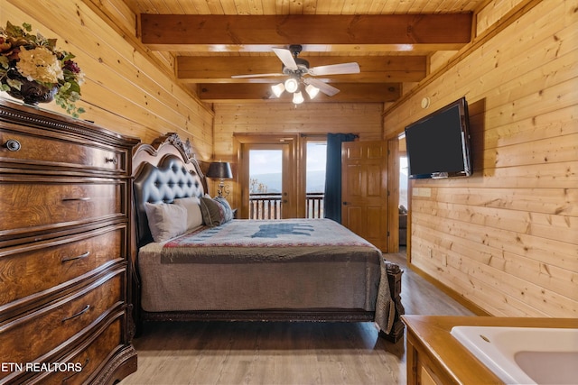 bedroom with beam ceiling, ceiling fan, dark wood-type flooring, and wood walls