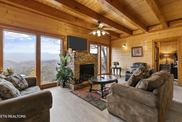 living room with ceiling fan, wooden walls, beam ceiling, wooden ceiling, and light hardwood / wood-style floors