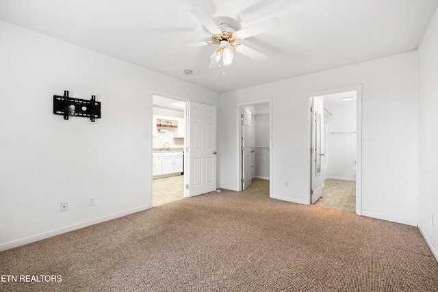 unfurnished bedroom featuring a spacious closet, a closet, ceiling fan, and light carpet