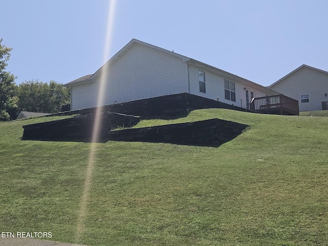 view of side of property featuring a wooden deck and a lawn