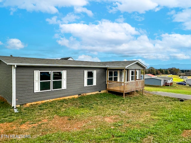 back of property with a lawn and a wooden deck