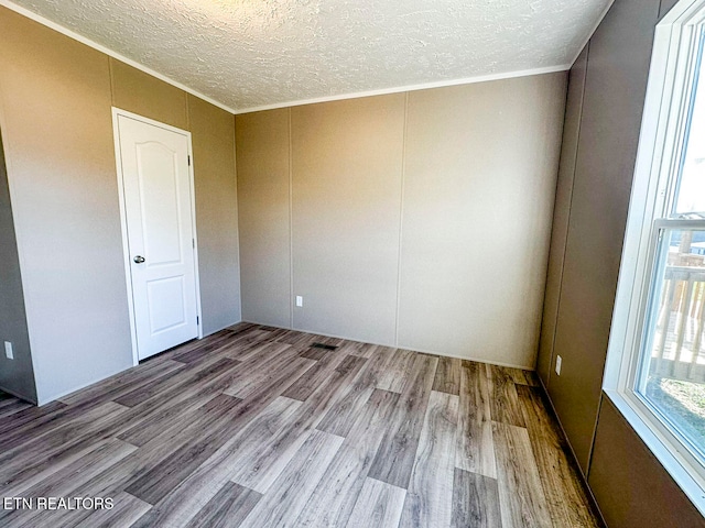 unfurnished room featuring light hardwood / wood-style flooring, a textured ceiling, and ornamental molding