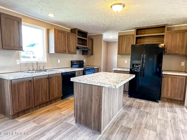 kitchen featuring sink, a kitchen island, black appliances, and light wood-type flooring