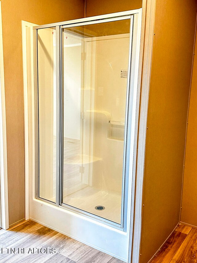 bathroom with a shower with door and hardwood / wood-style flooring