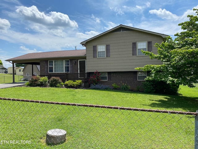 split level home with a carport, a front yard, brick siding, and fence