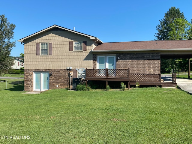 rear view of house featuring french doors, brick siding, a yard, a deck, and a carport