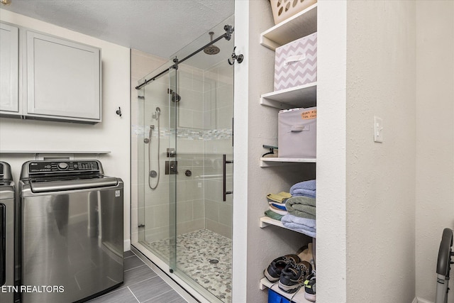 bathroom with a textured ceiling, separate washer and dryer, and a shower with shower door