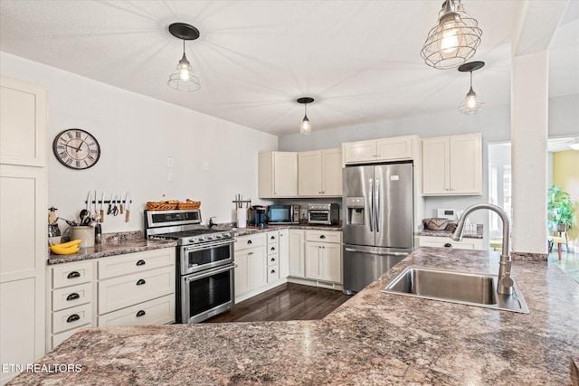 kitchen featuring dark wood-type flooring, white cabinets, sink, decorative light fixtures, and stainless steel appliances