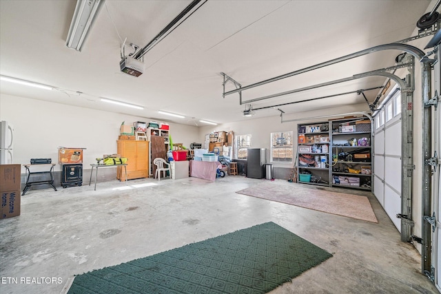 garage with a garage door opener and white refrigerator