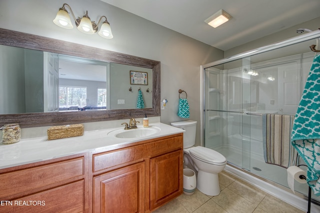 bathroom featuring tile patterned flooring, vanity, a shower with shower door, and toilet