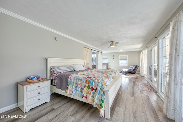 bedroom with ceiling fan, light hardwood / wood-style floors, a barn door, and crown molding