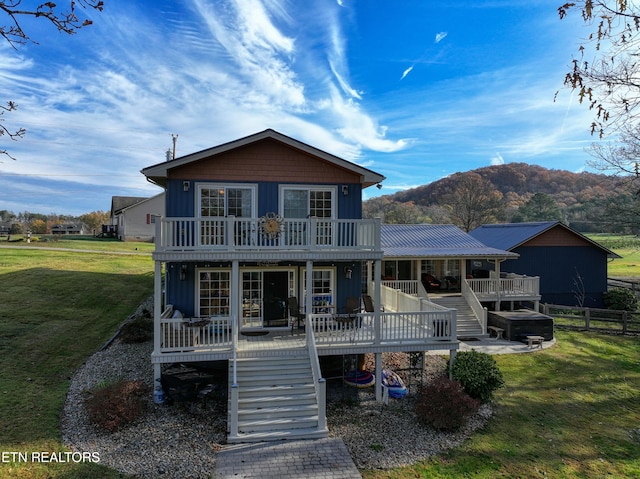 view of front of property with a deck with mountain view and a front lawn