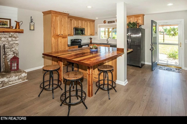 kitchen featuring wood counters, wood-type flooring, sink, and black appliances