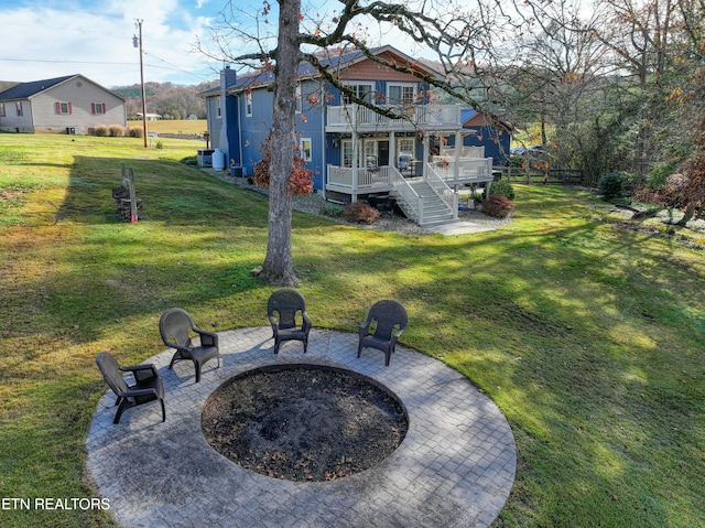 rear view of house with a yard, a balcony, a patio, and a fire pit