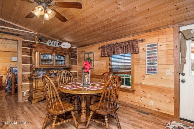 dining room featuring hardwood / wood-style floors, wood walls, lofted ceiling, and wood ceiling