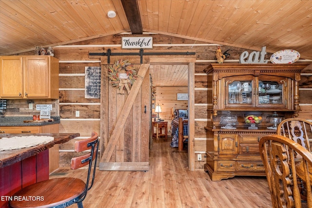 kitchen featuring wood ceiling, a barn door, light hardwood / wood-style floors, and wooden walls