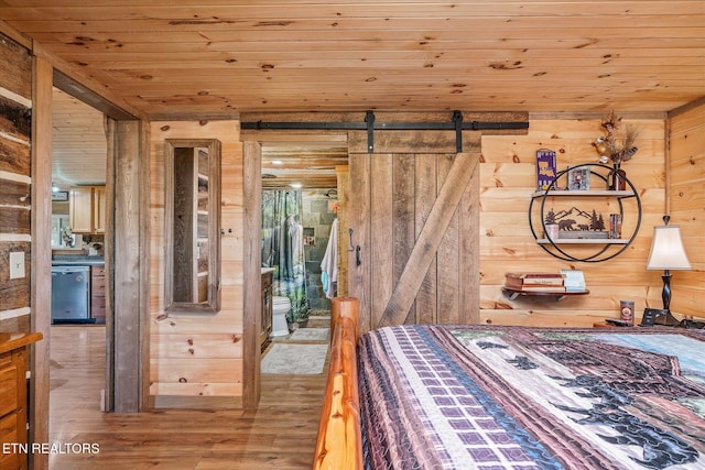 bedroom featuring wood ceiling, a barn door, wooden walls, and light hardwood / wood-style floors