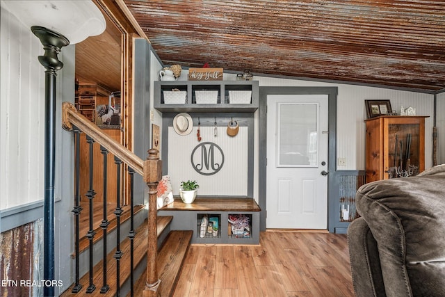 interior space with hardwood / wood-style floors, vaulted ceiling, and wood walls