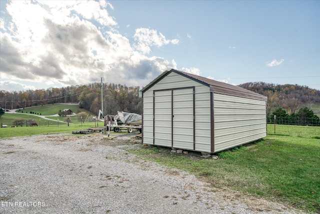 view of outdoor structure featuring a rural view and a lawn