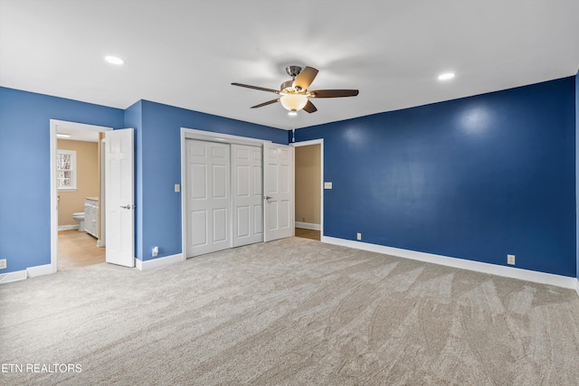 unfurnished bedroom featuring light carpet, a closet, ceiling fan, and ensuite bathroom