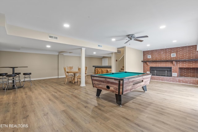 recreation room featuring a brick fireplace, ceiling fan, light wood-type flooring, pool table, and brick wall