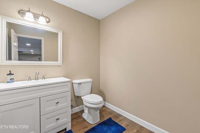 bathroom with toilet, vanity, and hardwood / wood-style flooring