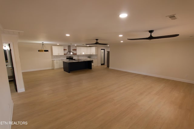 unfurnished living room featuring light hardwood / wood-style floors, ceiling fan, and sink