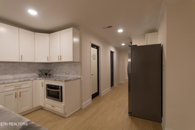 kitchen with stainless steel appliances, white cabinetry, and light hardwood / wood-style floors