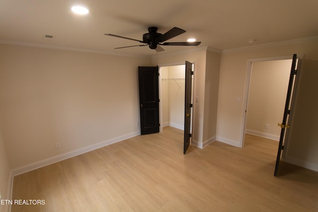 unfurnished bedroom featuring light wood-type flooring, a walk in closet, a closet, and ceiling fan