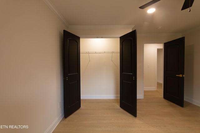 interior space featuring ceiling fan, light wood-type flooring, ornamental molding, and a closet