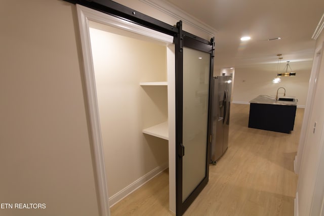 corridor featuring light hardwood / wood-style floors, a barn door, and sink