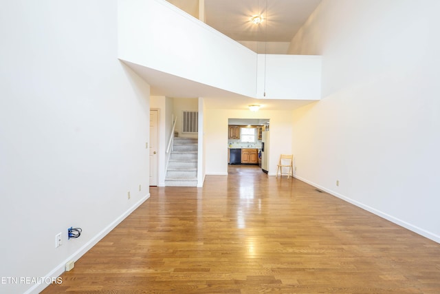 unfurnished living room featuring a high ceiling and hardwood / wood-style flooring