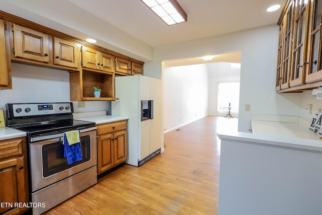 kitchen with white refrigerator with ice dispenser, light hardwood / wood-style floors, and stainless steel range with electric cooktop