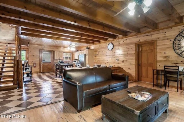 living room featuring ceiling fan, wooden ceiling, beamed ceiling, wood walls, and light wood-type flooring