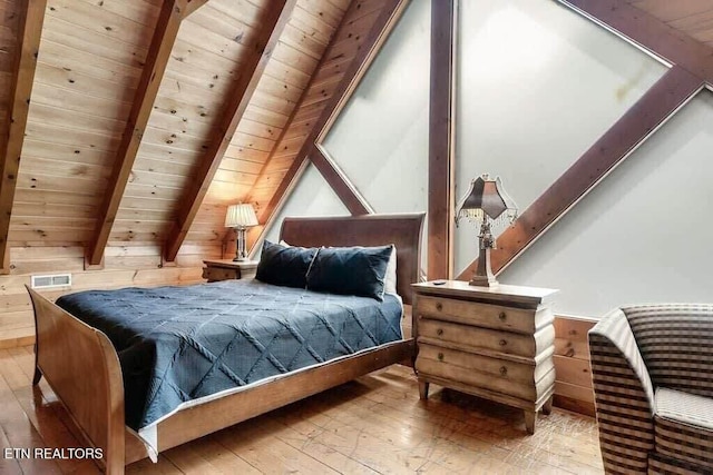 bedroom featuring beam ceiling, light hardwood / wood-style floors, wood ceiling, and wood walls