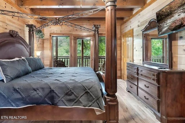 bedroom featuring beamed ceiling, wood walls, and multiple windows