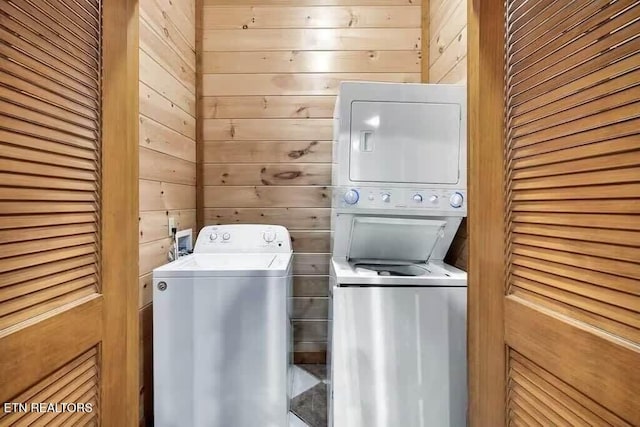 laundry room featuring stacked washer and dryer and wooden walls