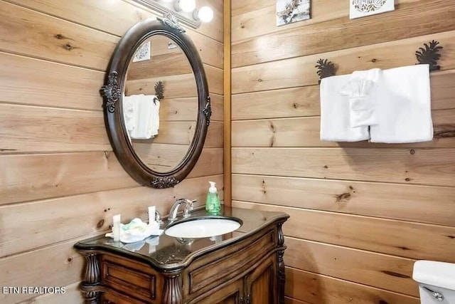 bathroom with vanity, toilet, and wooden walls