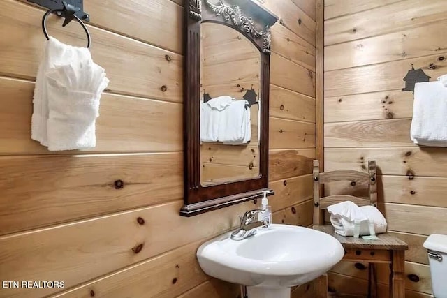 bathroom featuring wooden walls and sink