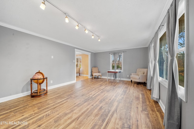 unfurnished room featuring hardwood / wood-style flooring, track lighting, and crown molding