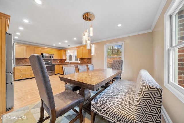 dining space featuring ornamental molding, sink, a wealth of natural light, and light wood-type flooring