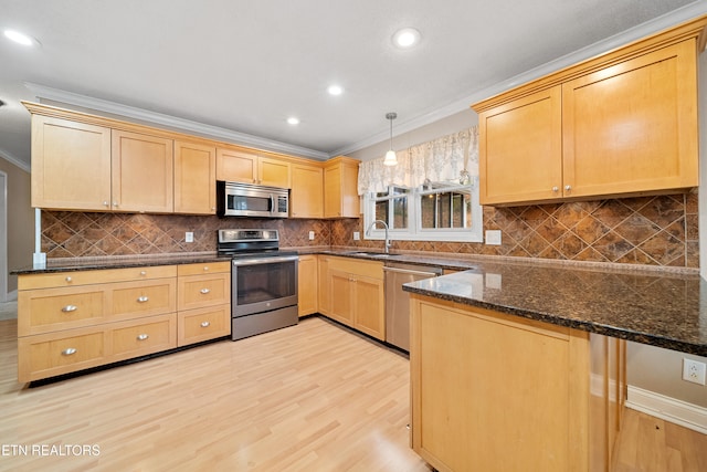 kitchen with sink, crown molding, appliances with stainless steel finishes, dark stone countertops, and decorative light fixtures